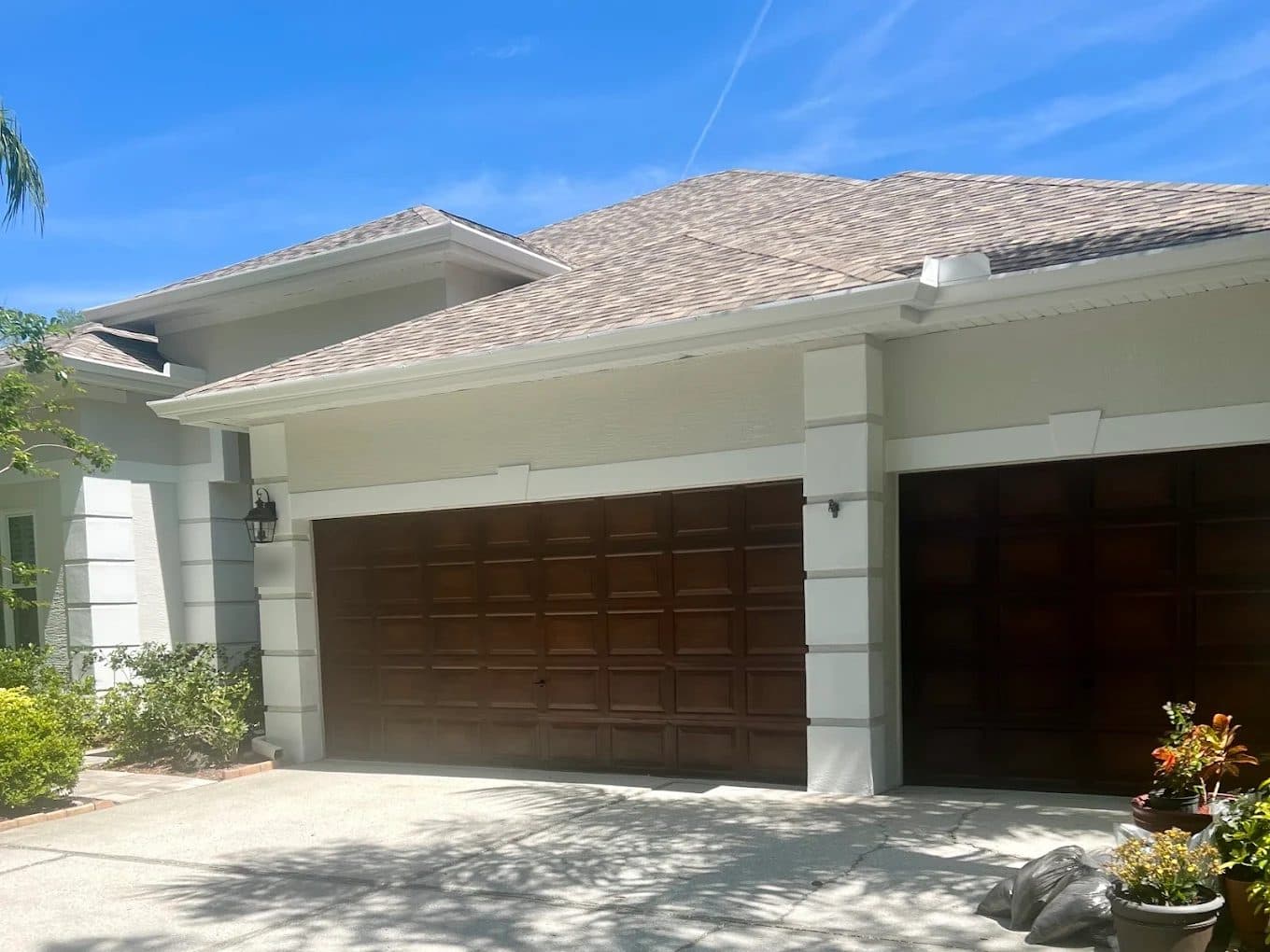 Wood-finish garage doors framed by freshly painted gray stucco