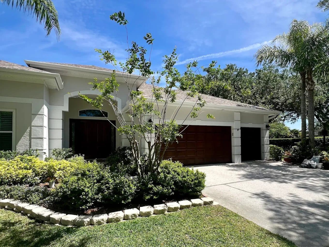Gray stucco home with white trim and wood-finish garage doors