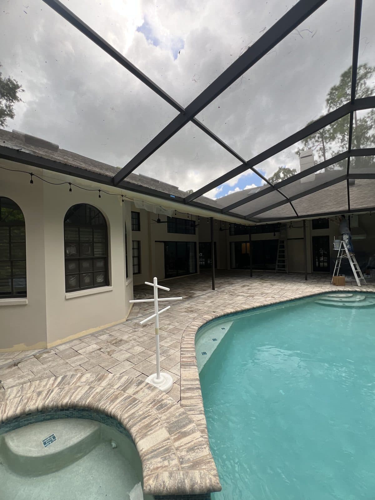 Stucco walls and arched windows painted around a screened pool enclosure