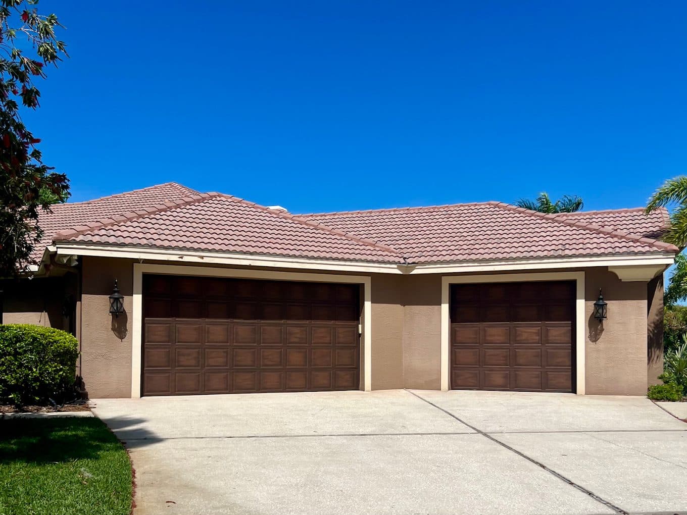 Three-car garage with wood-grain doors and repainted stucco